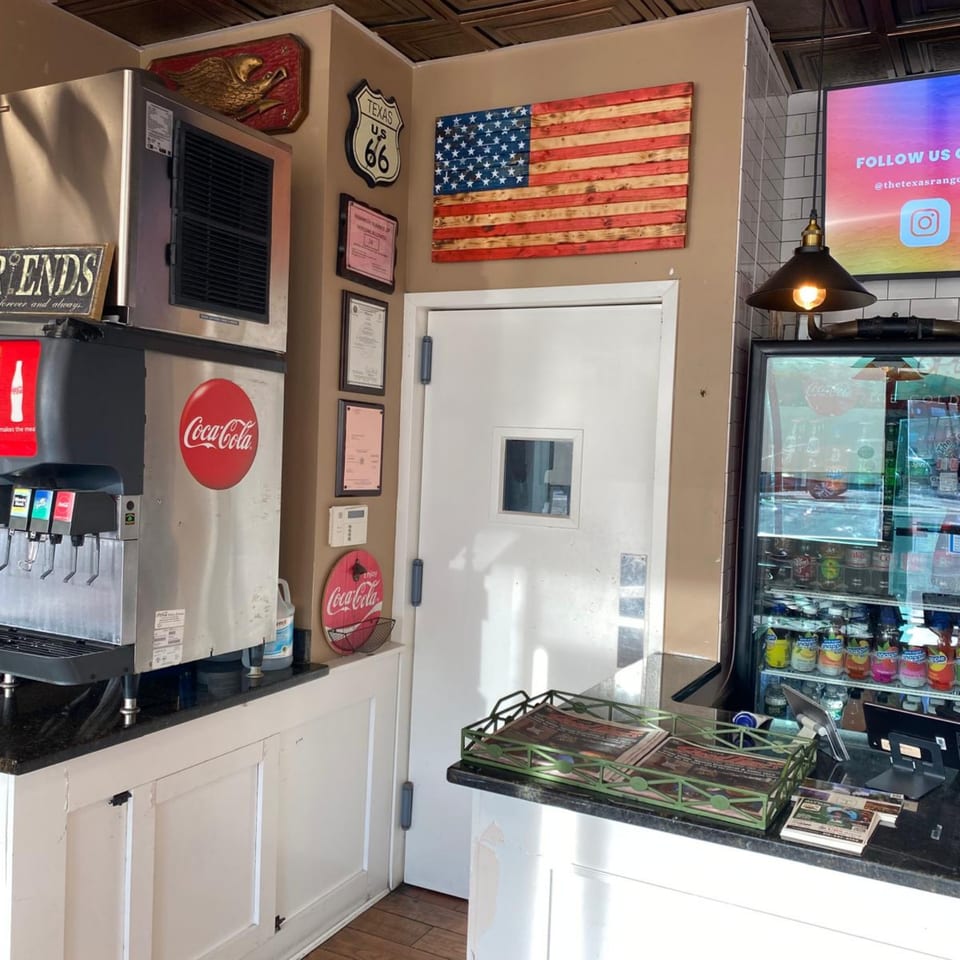 A soda fountain, drink cooler, and American flag decor in The Texas Ranger burger restaurant.