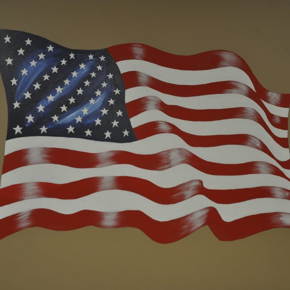Waving American flag mural with red and white stripes and a blue field with white stars.