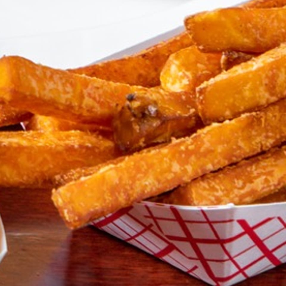 Golden-brown, crispy Texas Ranger fries in a red and white checkered paper tray.