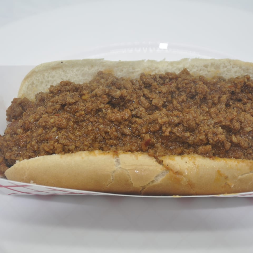 A Texas Ranger sloppy joe, a hot dog bun filled with seasoned ground meat, in a paper tray.