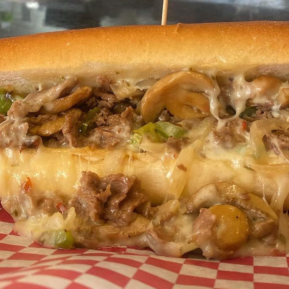 Close-up of a Texas Ranger cheesesteak sandwich, filled with steak, melted cheese, mushrooms, and peppers.
