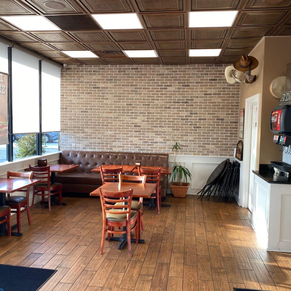 Interior of The Texas Ranger restaurant with brick walls, wooden tables, and a brown leather booth.