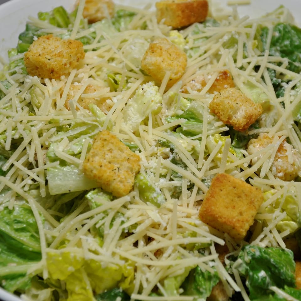 Close-up of a Caesar salad with romaine lettuce, shredded Parmesan cheese, and croutons.