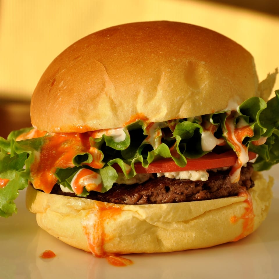 A Texas Ranger burger with lettuce, tomato, and sauces on a bun.