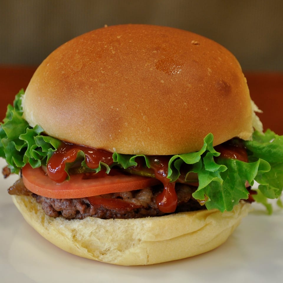 A Texas Ranger burger with a juicy patty, fresh lettuce, tomato, and ketchup on a bun.