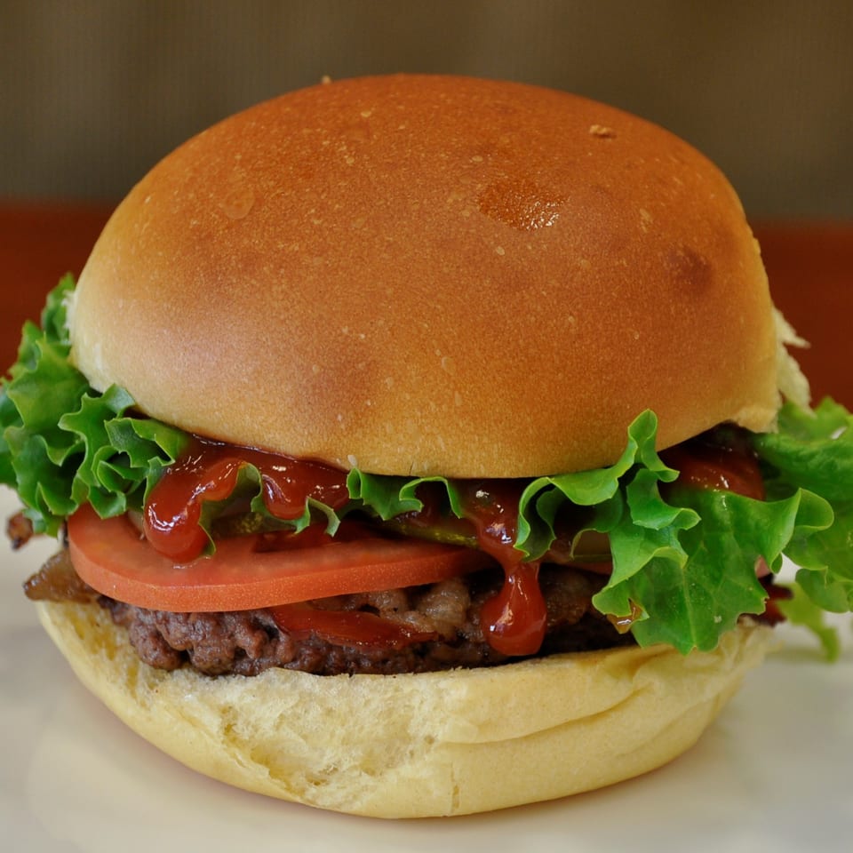A Texas Ranger burger with a juicy patty, fresh lettuce, tomato, and ketchup on a bun.